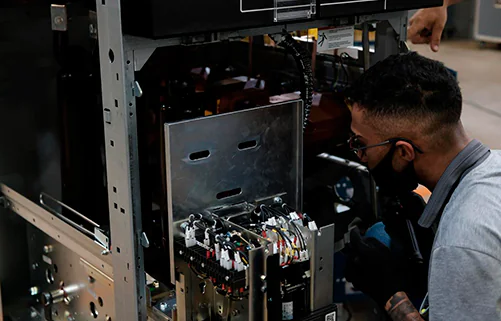 Painéis elétricos industriais da AMC Soluções em galpão de montagem, com fileiras simétricas de quadros de comando.
