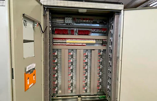 Painéis elétricos industriais da AMC Soluções em galpão de montagem, com fileiras simétricas de quadros de comando.