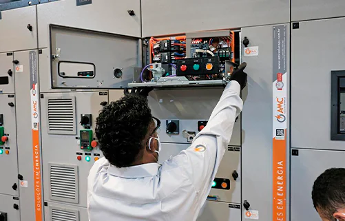 Painéis elétricos industriais da AMC Soluções em galpão de montagem, com fileiras simétricas de quadros de comando.